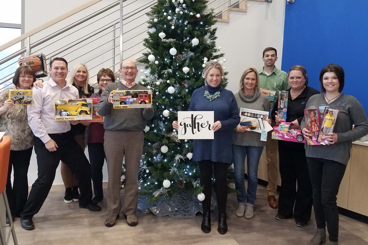 Accel Foundation - The Accel Team in Front of Holiday Tree While Holding Gifts for Charity