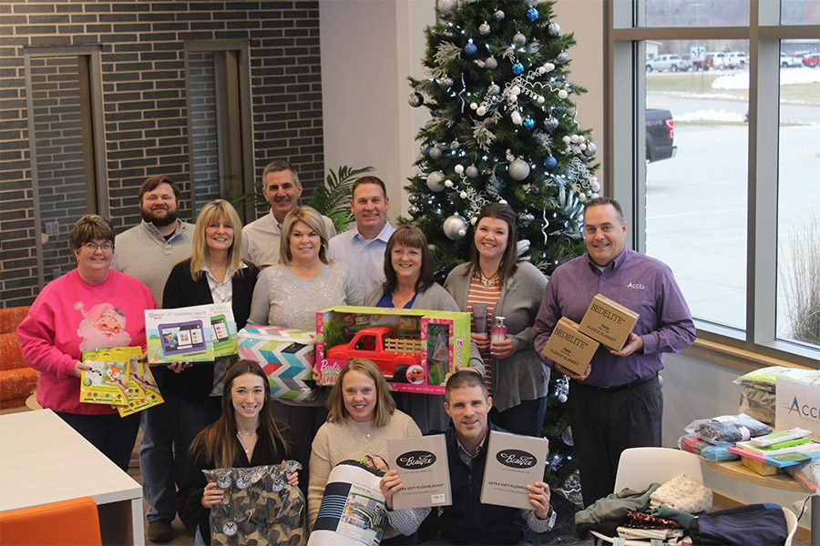 The Accel Foundation - Adopt a family gifts event with Accel Foundation Team Smiling and Holding Gifts in Front of a Tree in the Office